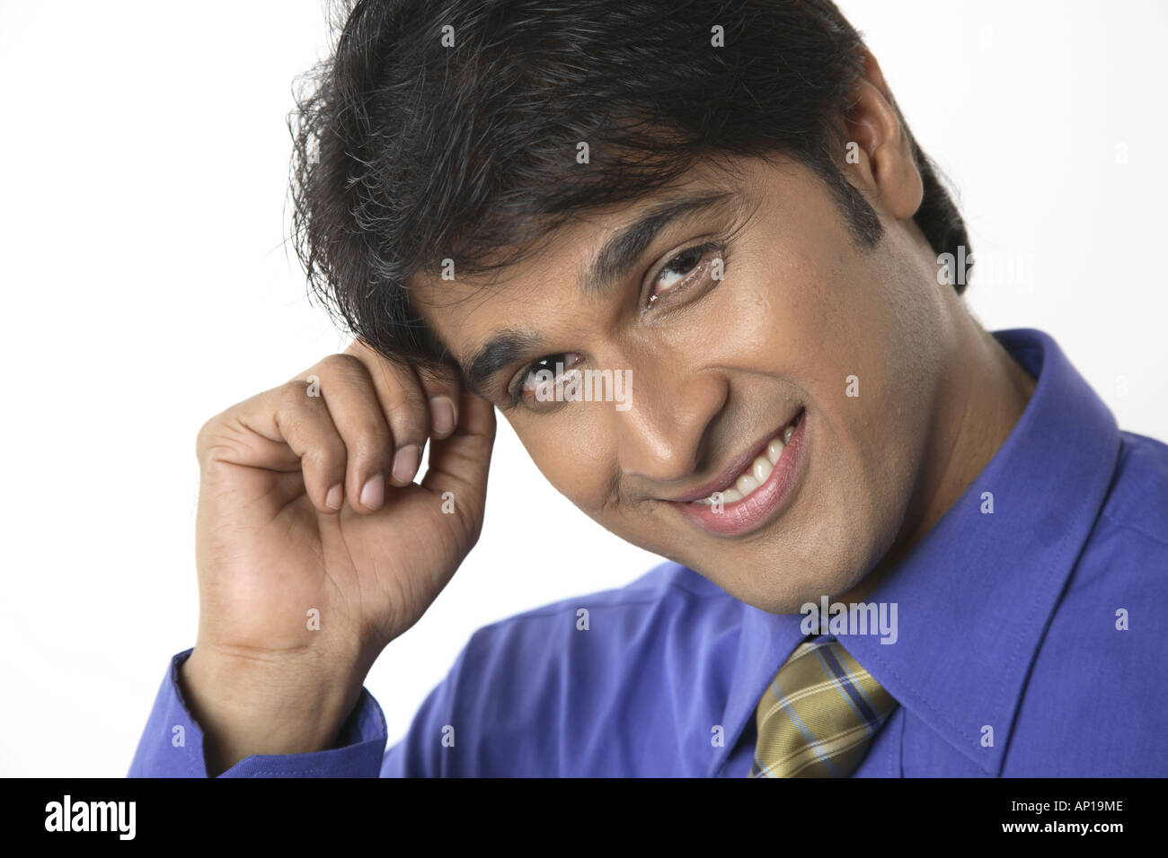 ANG200140 Executive touching his forehead with hand looking into camera and smiling Model release No 687M Stock Photo