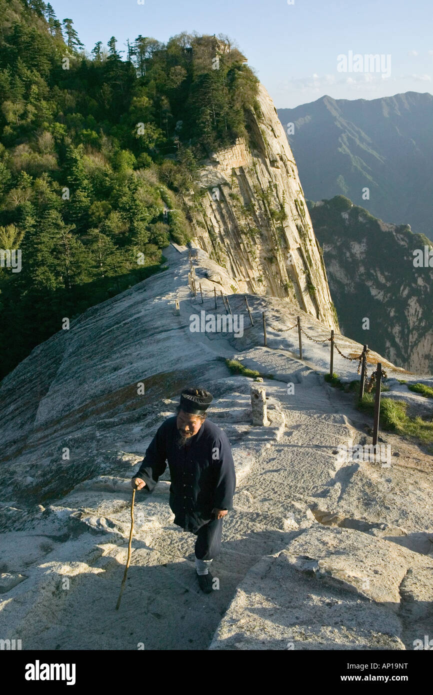 daoist monk on Fish Back Ridge, approaching Cui Yun Gong Monastery on South Peak, pilgrim path along stone steps with chain hand Stock Photo