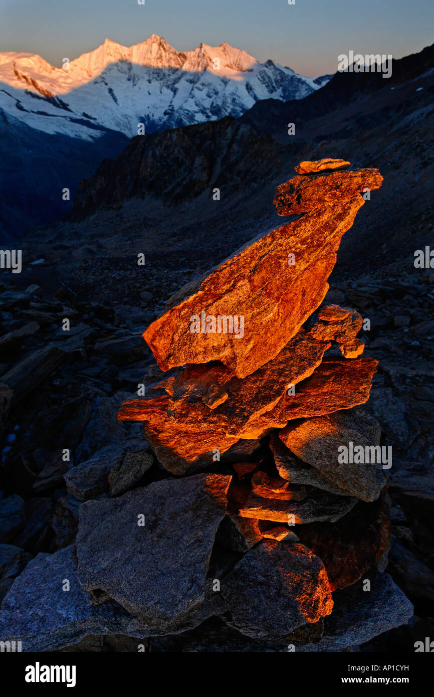Canton Valais, a cairn at sunrise at the Zwischenbergpass on the way to the Weissmies (4017 m). In the background the fourthause Stock Photo