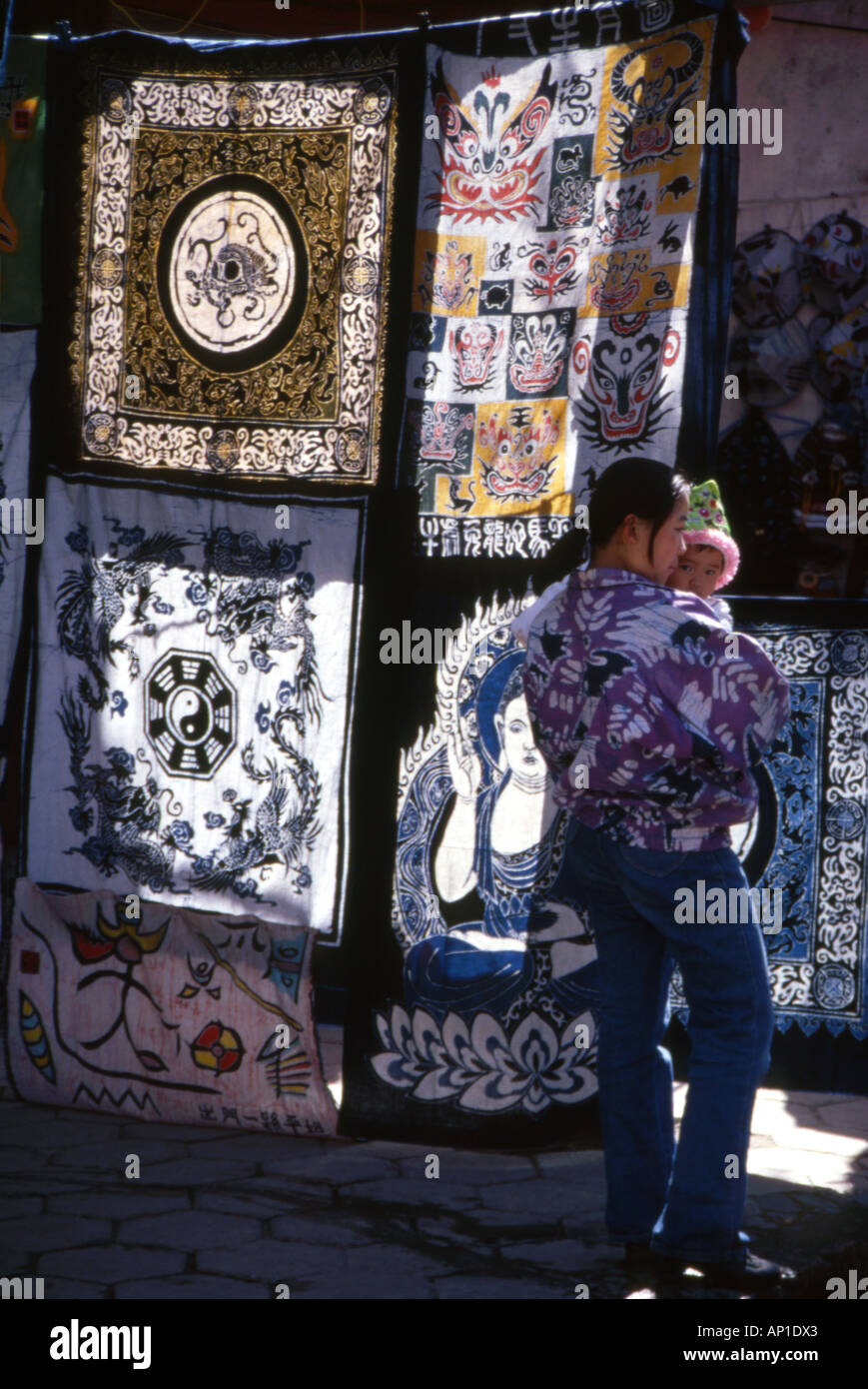 Local woman carrying her child past a stall of back lit quilts on sale,Chengdu,Sichuan province,China. Stock Photo