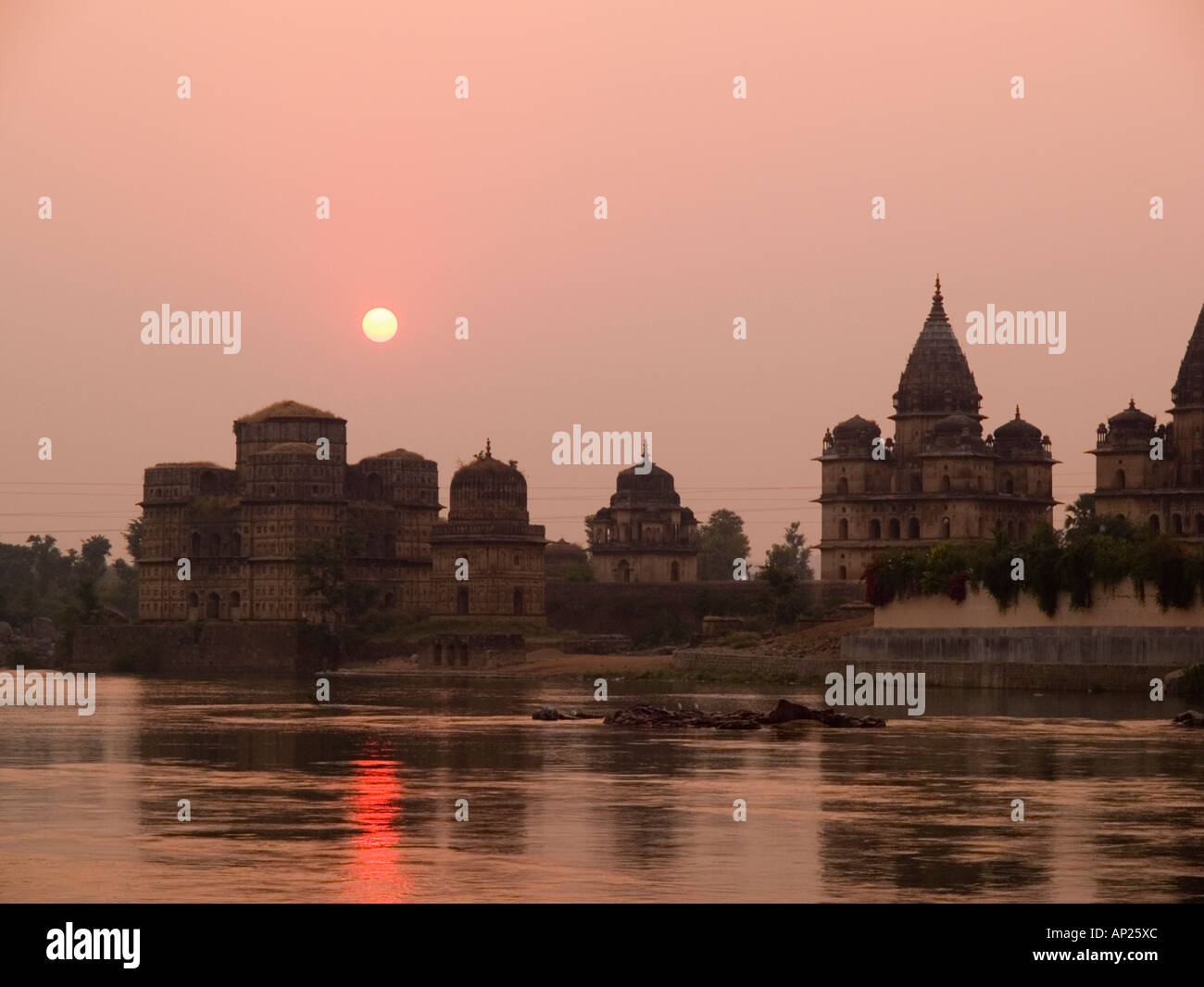 Orchha Madhya Pradesh India. Betwa River at sunset with sun setting behind domes and spires of Chhatris Bundela Stock Photo