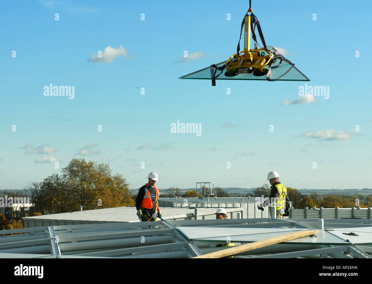 Workmen on the roof of the Grand Arcade development in Cambridge England positioning one of the triangular glass roof panels Stock Photo