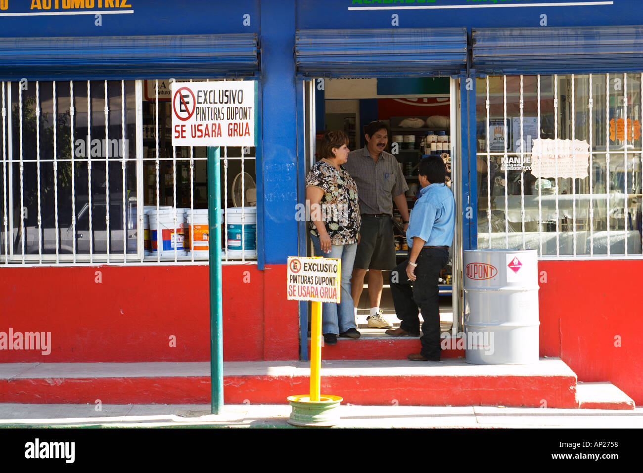 MEXICO Cabo San Lucas Woman and two men stand in doorway and talk no parking signs colorful building Stock Photo
