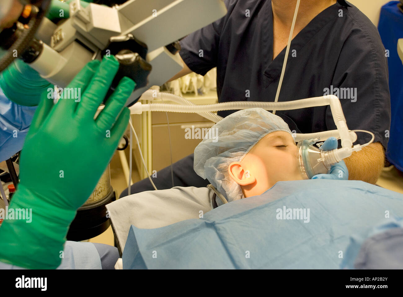 Surgical team performing ear surgery on young boy in hospital operating