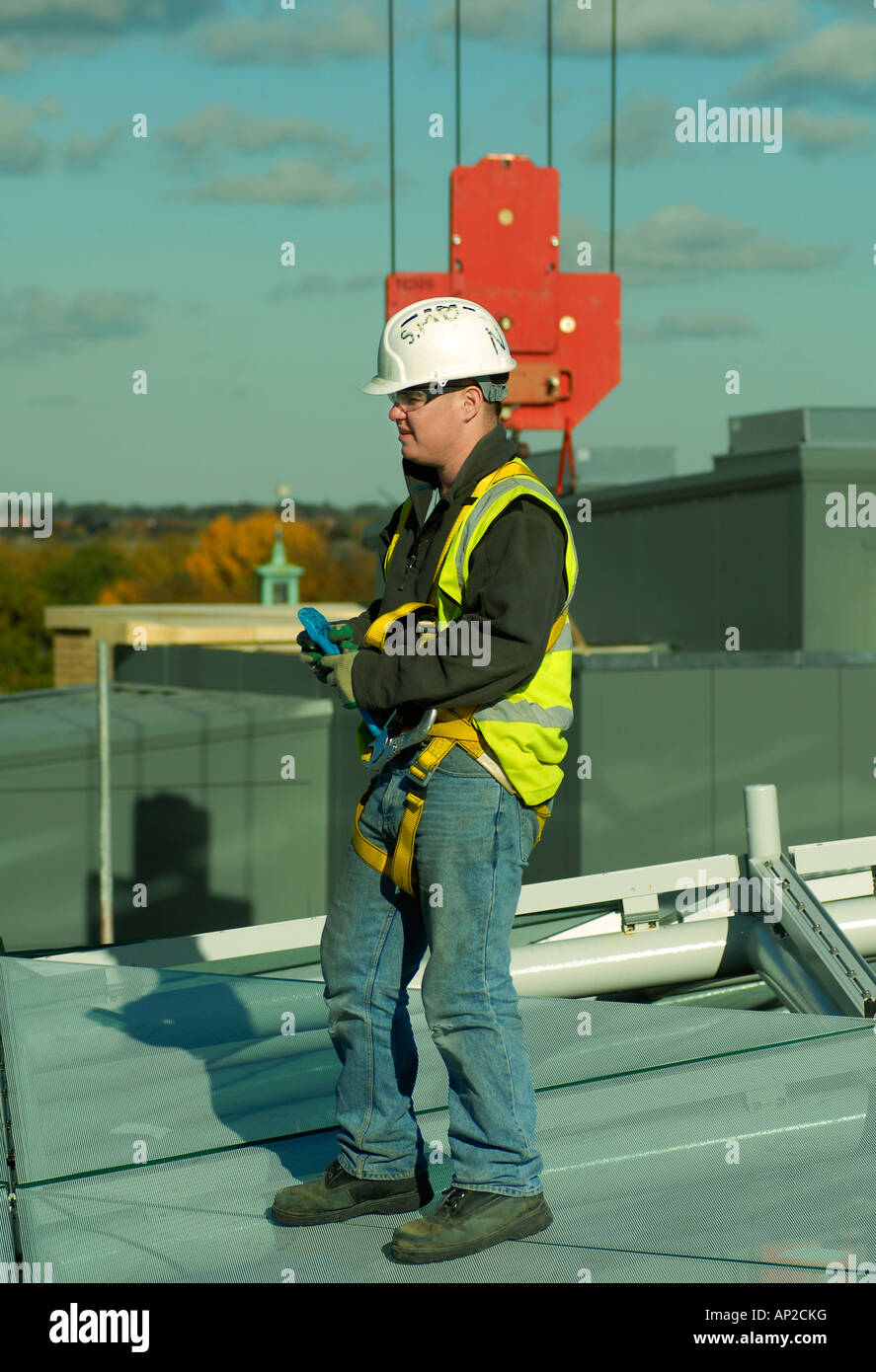 Workman wearing safety equipment on the roof of the Grand Arcade development in Cambridge as glass panels are being installed Stock Photo