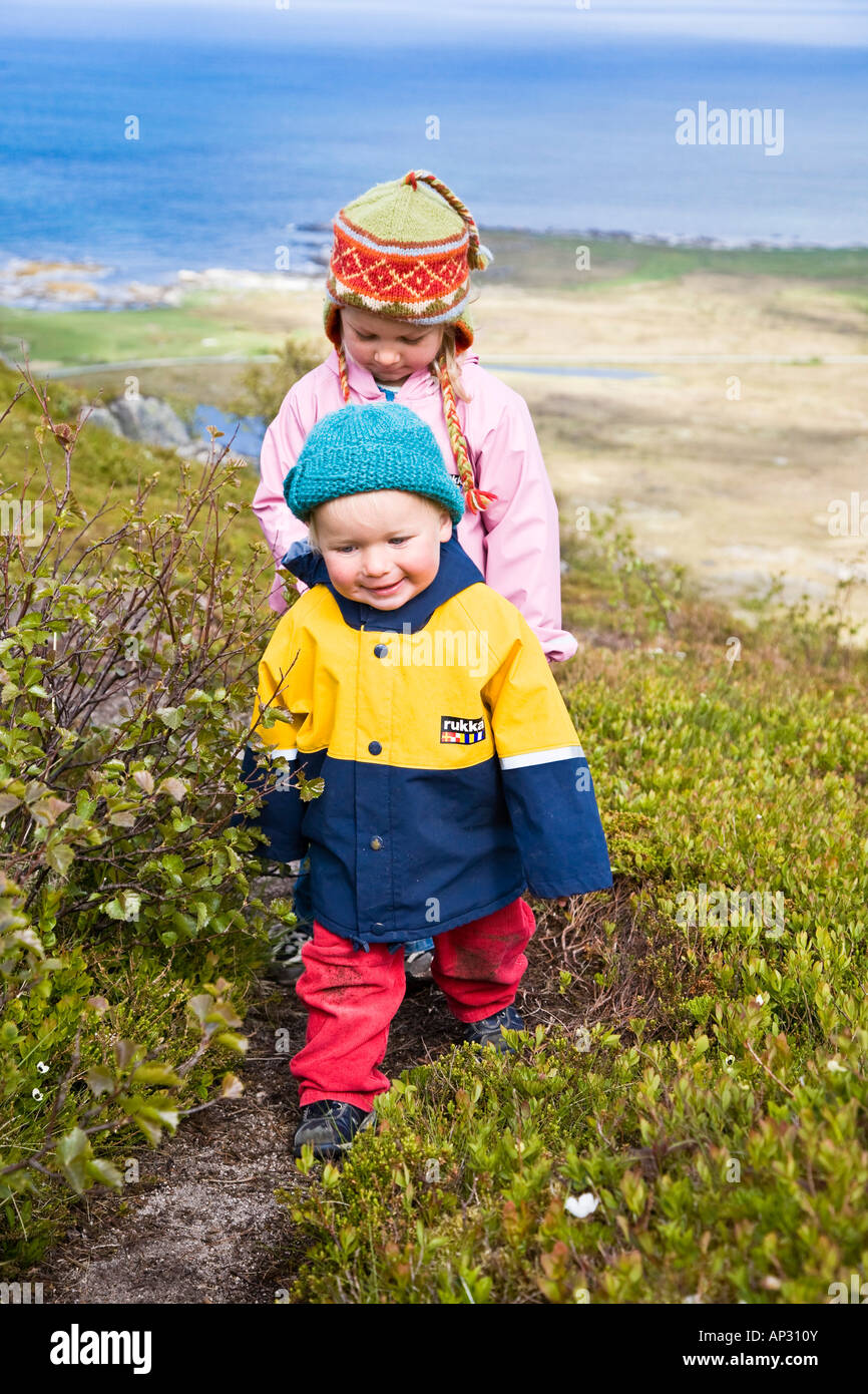 Two small girls, children, in raincoats walking along the beach, Gimsoya Island, Lofoten, Norway Stock Photo