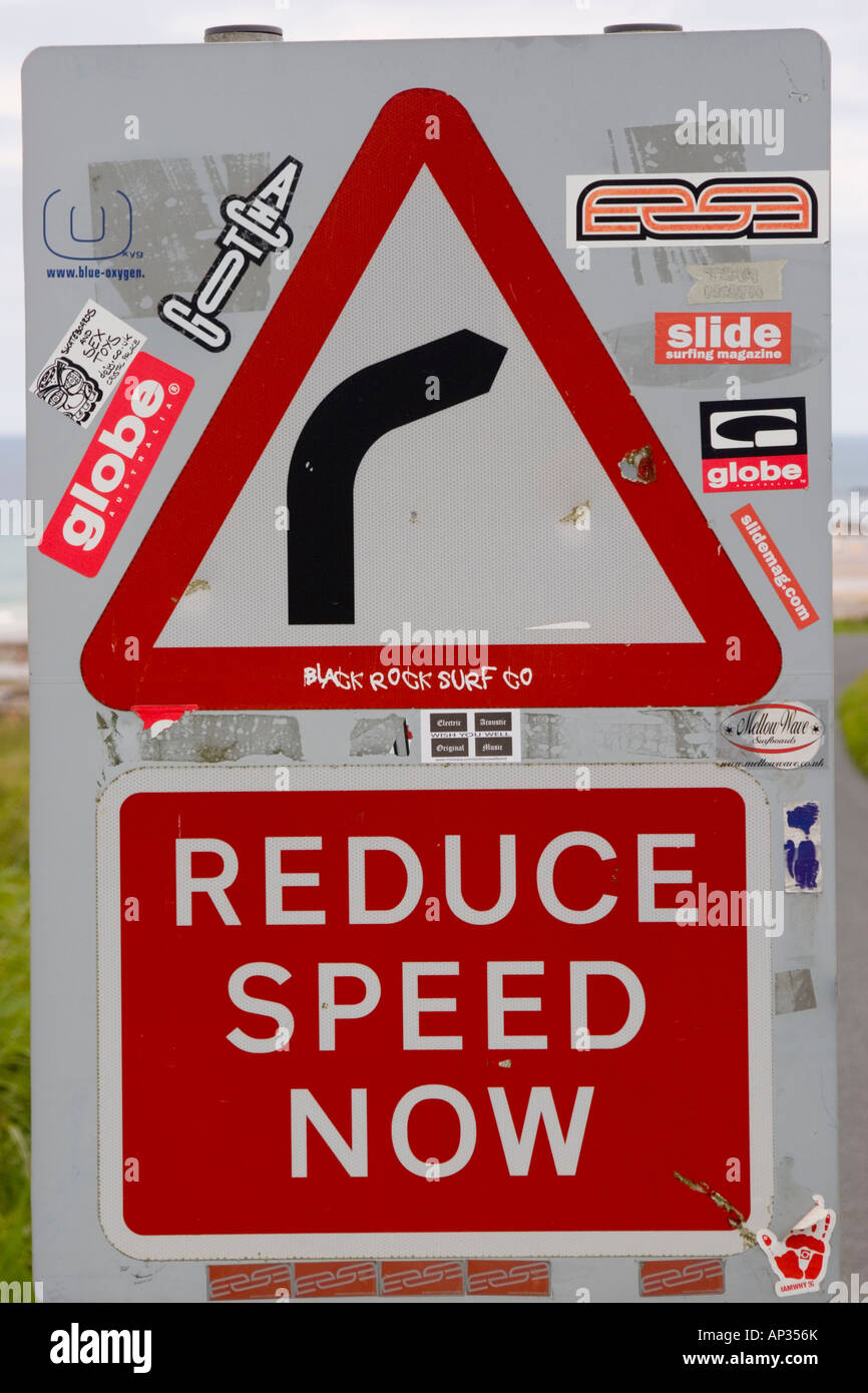 Road sign warning of dangerous bend and Reduce speed now Stock Photo