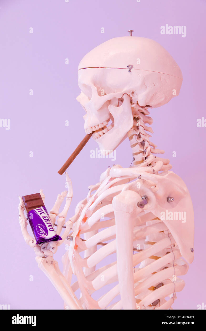 bar of chocolate and a cigarette A human skeleton smoking a cigar with a bar of chocolate Stock Photo