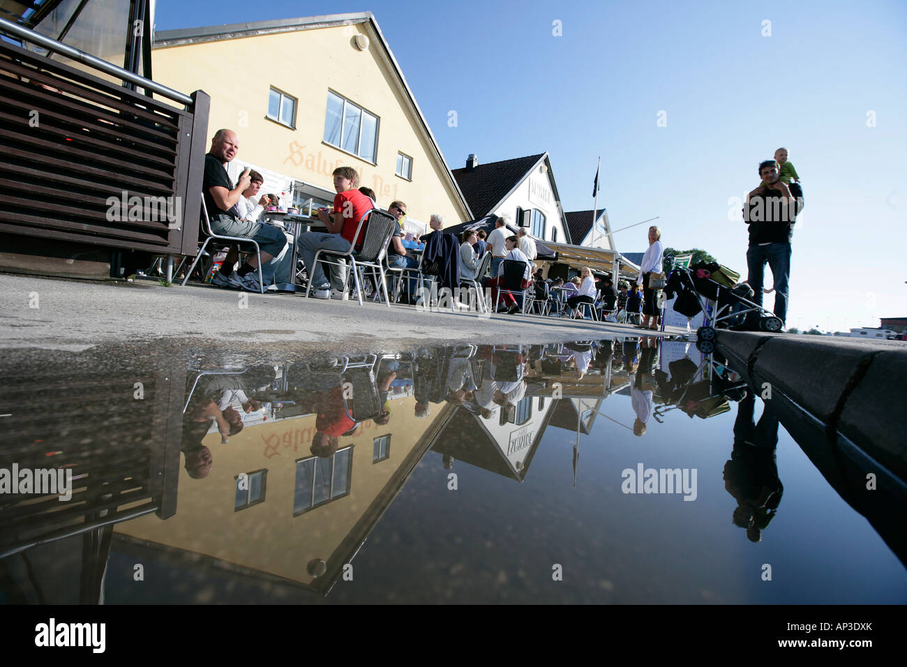 Cafes, quayside promenade, with reflection in a puddle, Visby, Gotland, Sweden Stock Photo