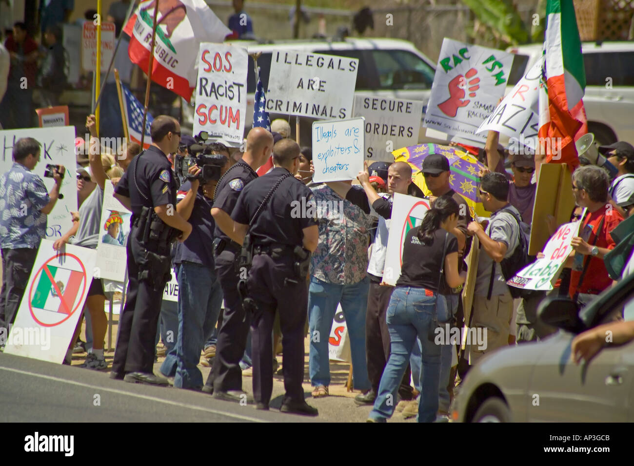 Police question counter demonstrators's sign at pro-day laborer demonstration at a hiring site in Laguna Beach, CA. Stock Photo