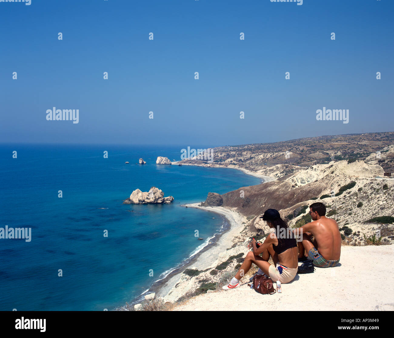 Couple sitting at a lookout over Aphrodite's Rock (or Petra tou Romiou), near Pissouri, West Coast, Cyprus Stock Photo