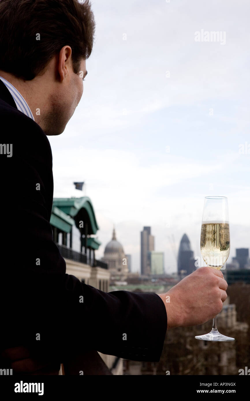 man drinking champagne on Swissotel The Howard hotel terrace overlooking the City of London Stock Photo