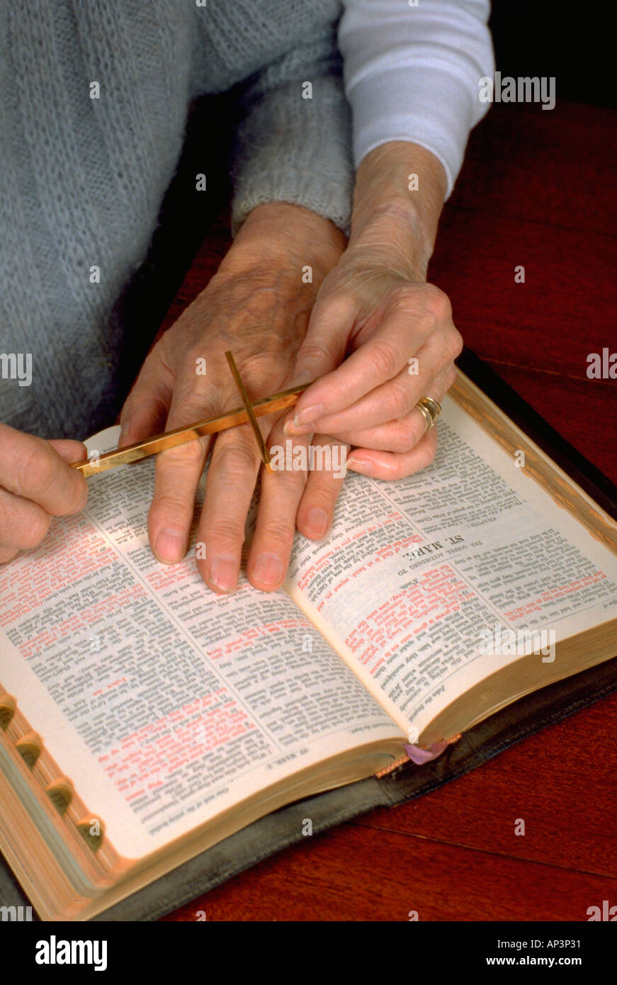 Hands of spouses age 88 and 75 with cross reading the bible. Minneapolis Minnesota MN USA Stock Photo
