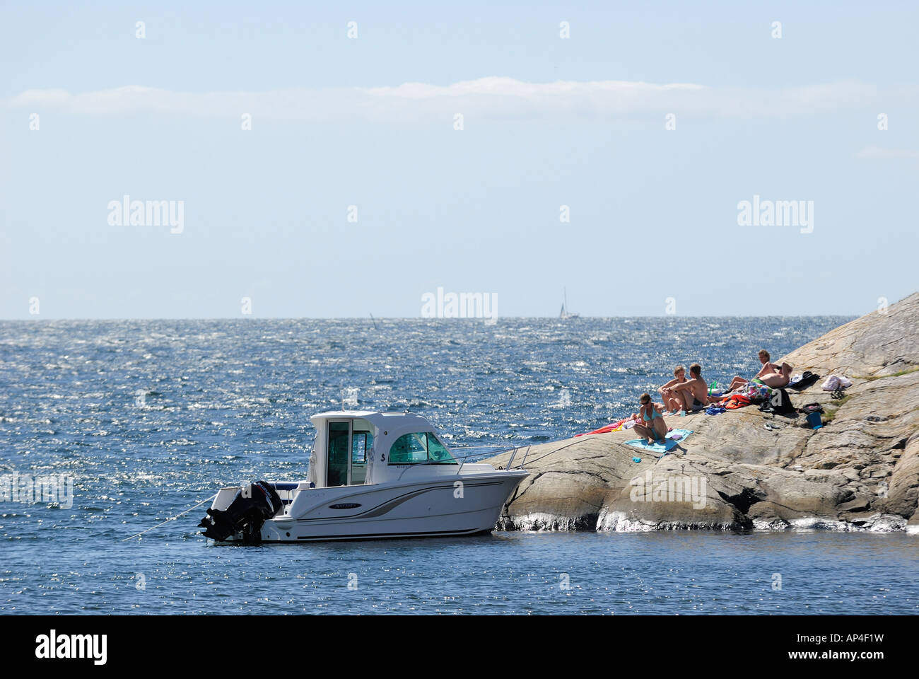 Tourists sitting on rock by sea, Vargö, Göteborgs Södra skärgård, Sweden Stock Photo