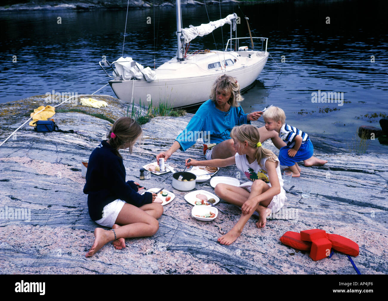 family in the swedish archipelago having a meal on a rock on a sailing trip Stock Photo