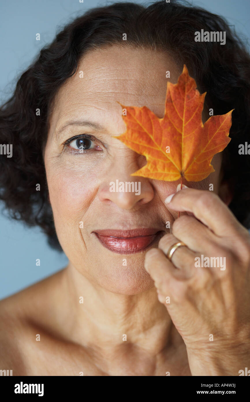 Senior African woman holding autumn leaf over eye Stock Photo