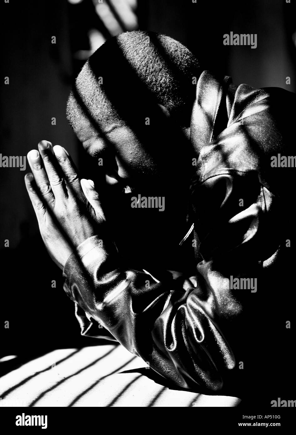 Young man praying for the safety of his country Zimbabwe Kneeling down hands together Stock Photo