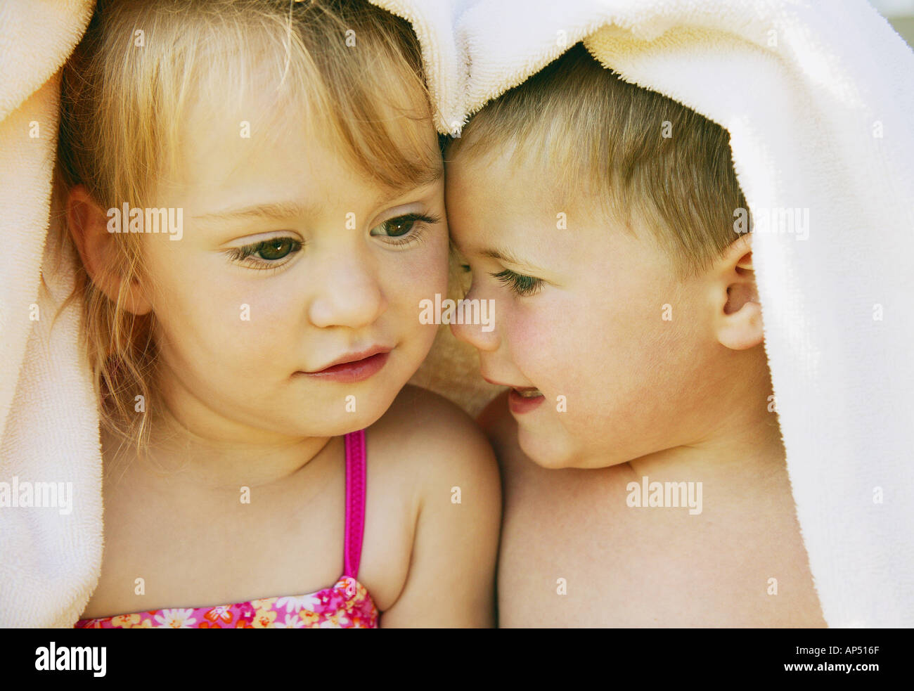 Two kids snuggle under a towel Stock Photo Alamy