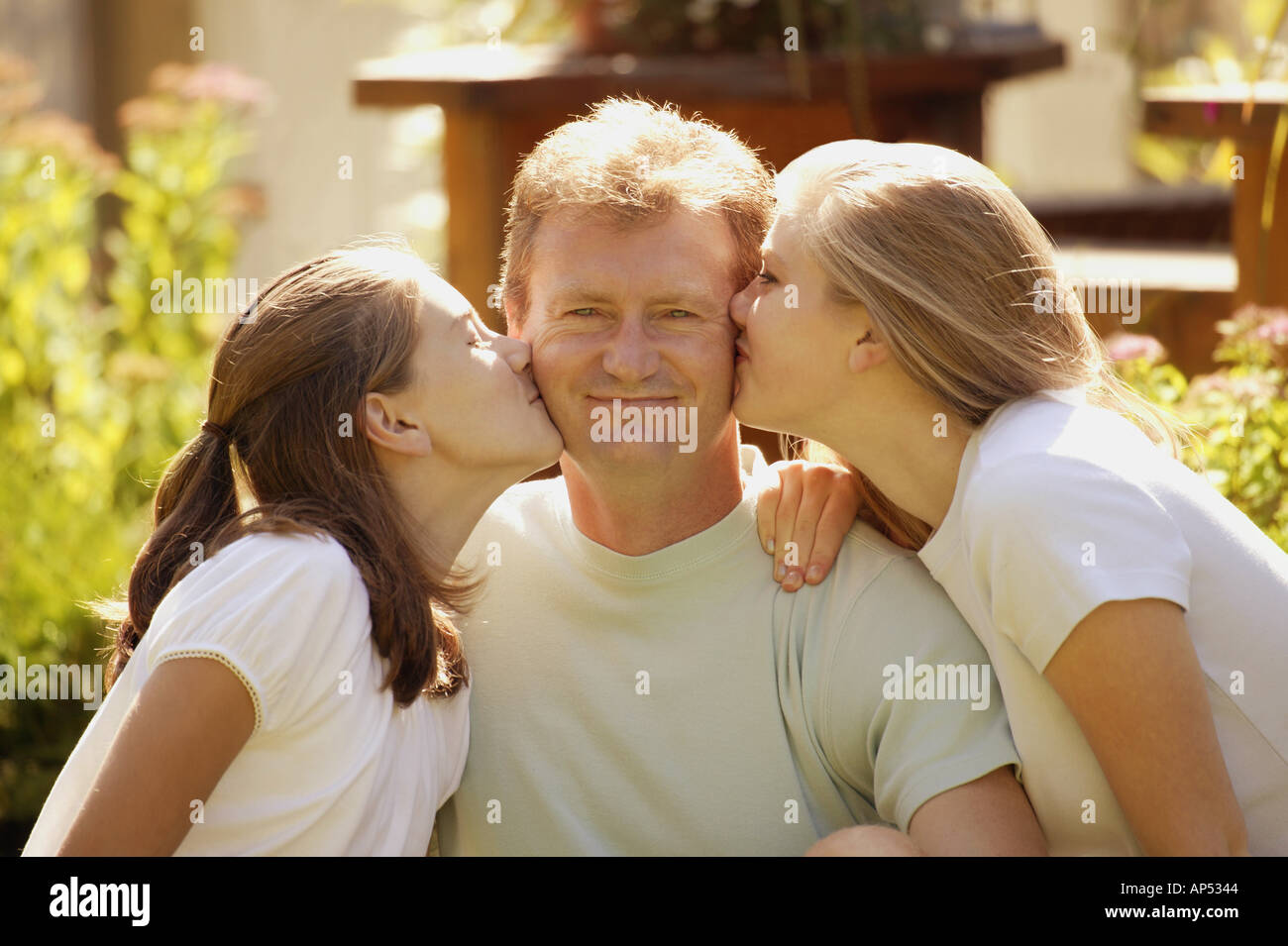 Two girls kiss father Stock Photo