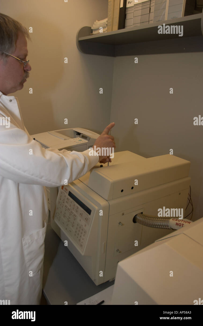 Toxicologist using a gas chromatograph to test a sample for traces of