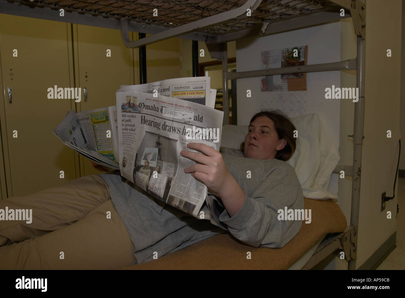 Female inmate reading the newspaper resting on her bed Nebraska Correctional Center for Women Stock Photo