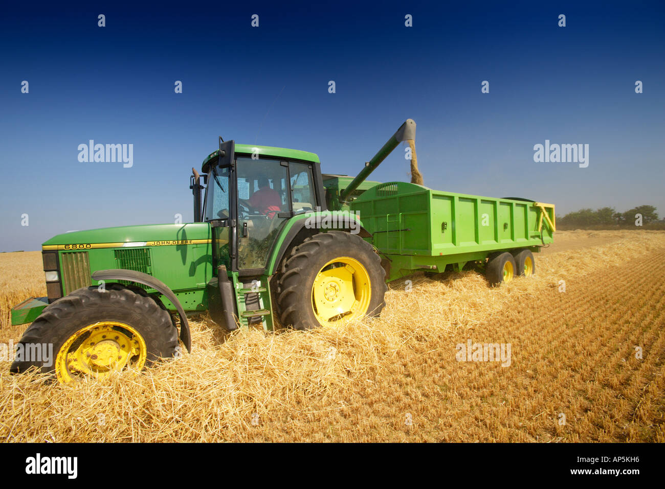 John Deere Combine Harvester and Tractor With Trailer Collecting Crop