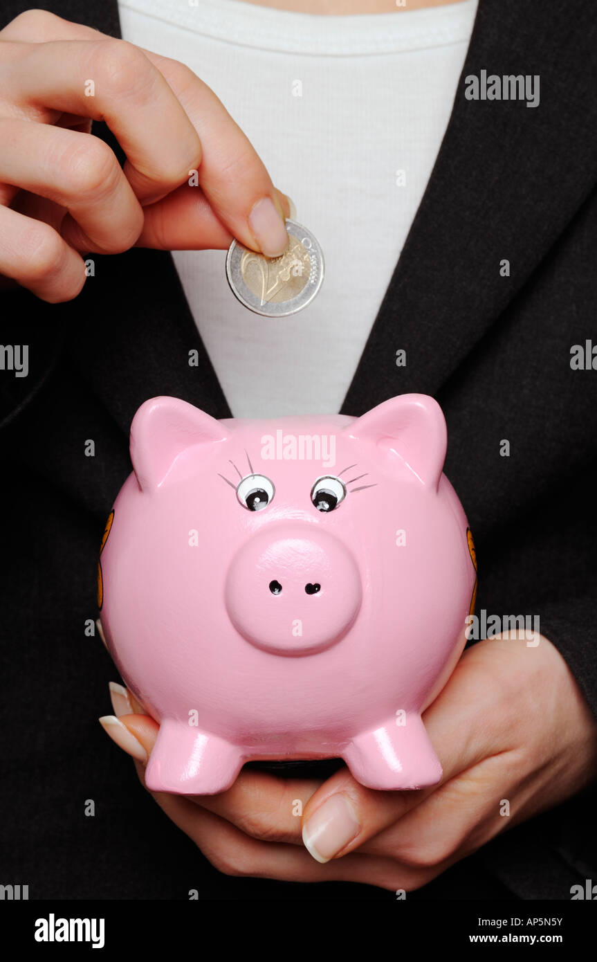 Savings Image of a Business Woman Putting a Euro Coin Into a Piggy Bank Stock Photo