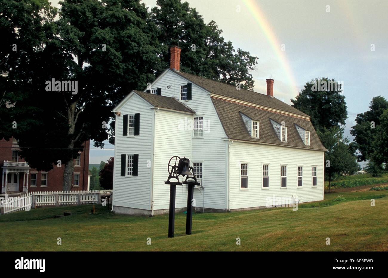 New Gloucester, ME A rainbow rises from behind the Meetinghouse at the Sabbathday Lake Shaker Village. Stock Photo