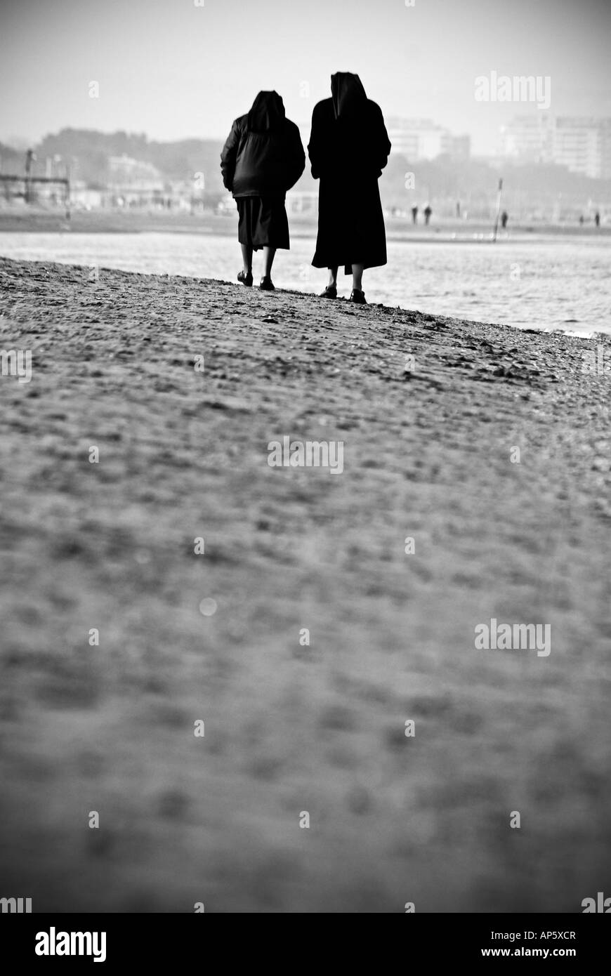 Sisters walking and talking on seaside Stock Photo