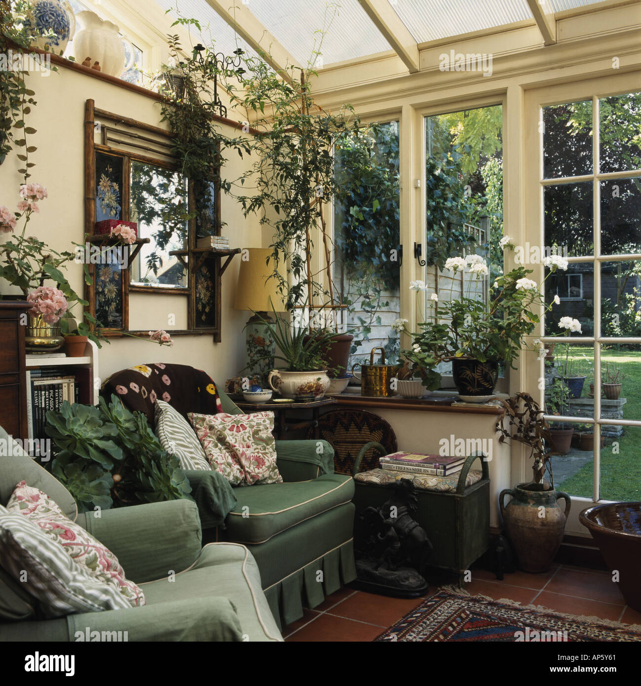 Comfy green armchairs in traditional conservatory living room with