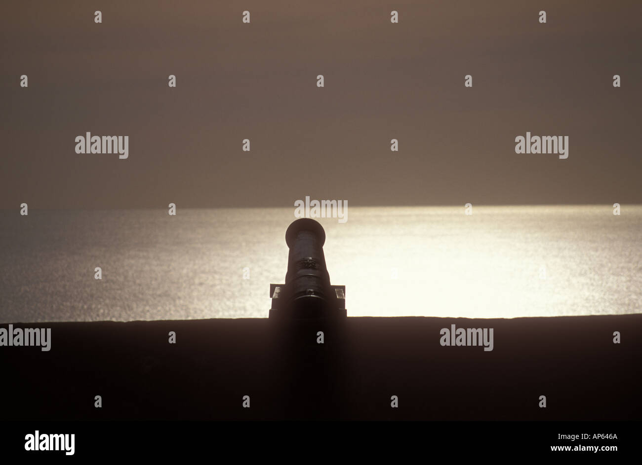 silhouette of cannon at dusk overlooking a glassy sea Stock Photo