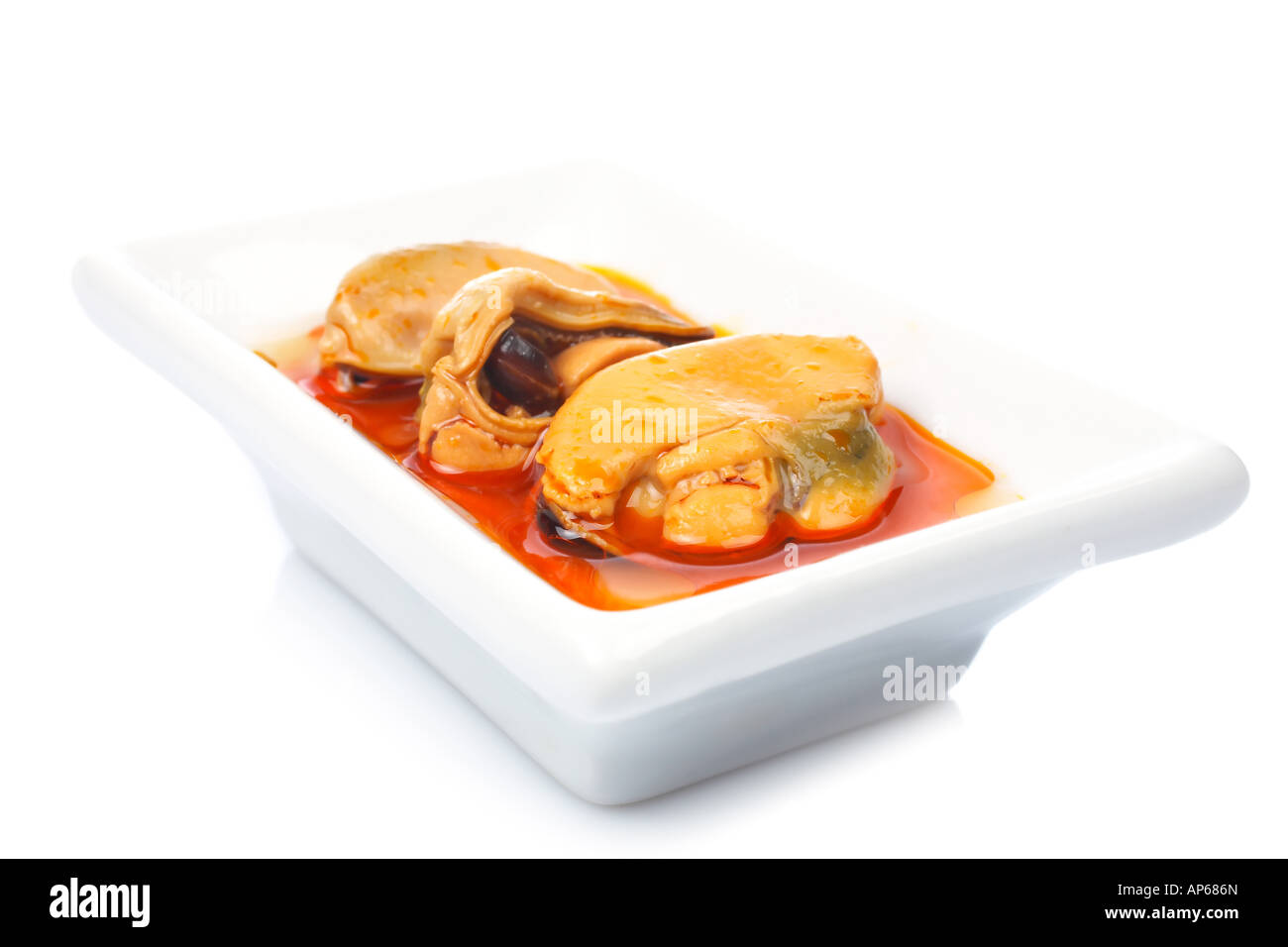 Some mussels just cooked in a white dish for a good meal reflectd on white background Shallow DOF Stock Photo
