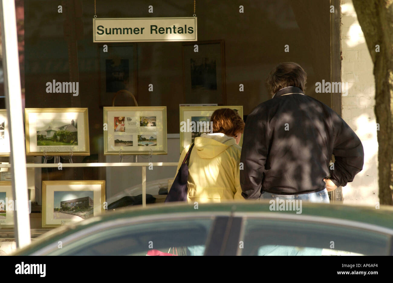 East HAmpton NY A couple looks at photos of summer rentals in the window of East Hampton Village