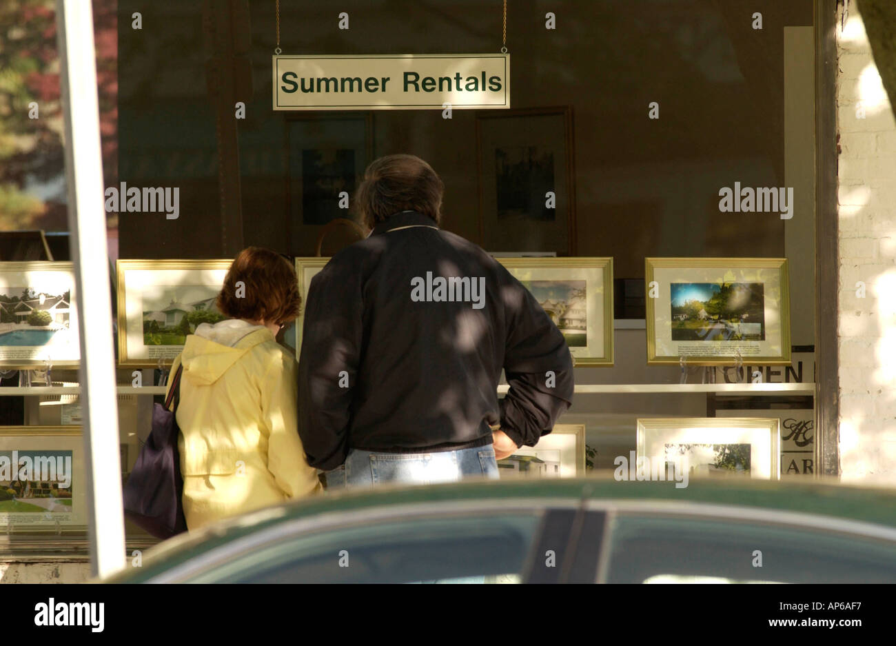 East HAmpton NY A couple looks at photos of summer rentals in the window of East Hampton Village