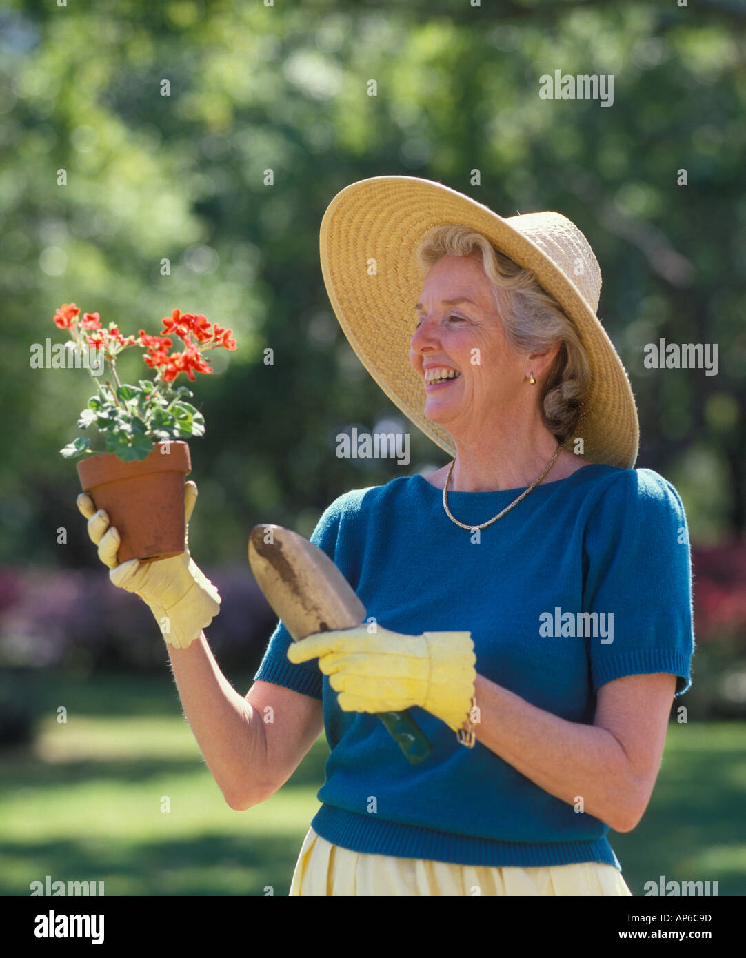 mature woman examining a potted plant in garden Stock Photo