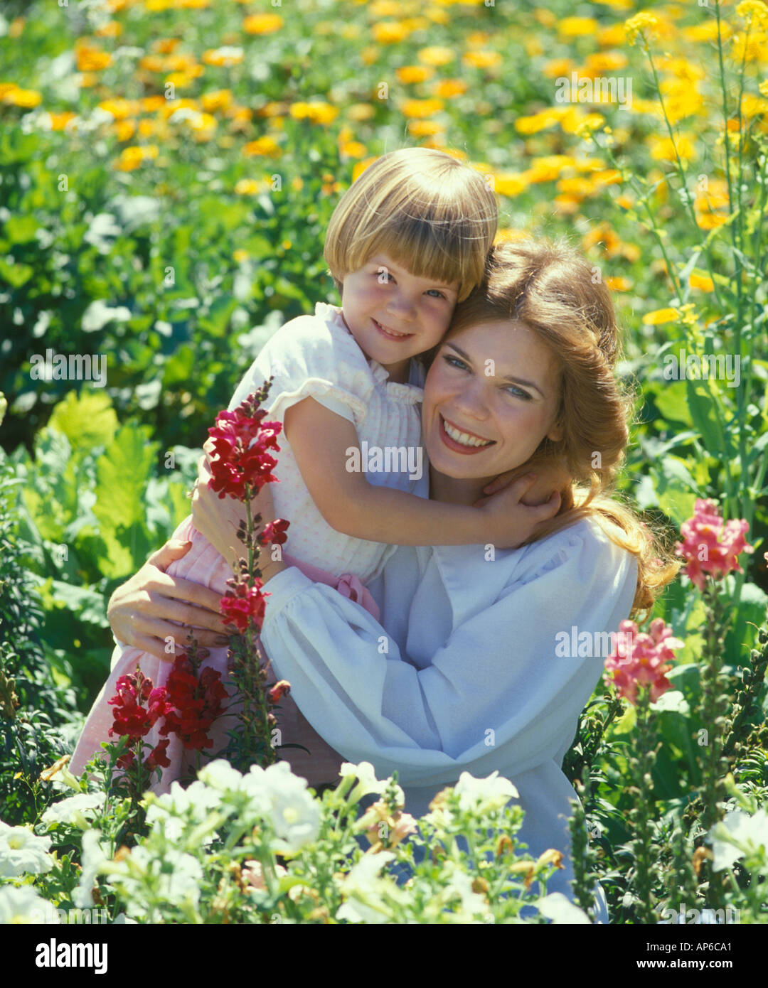 mother and daughter embracing in flower garden Stock Photo