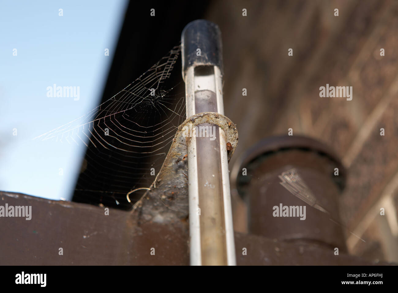 Old rusty steel domestic oil storage tank sited next to a window, flue