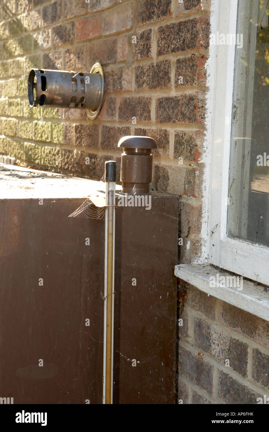Old rusty steel domestic oil storage tank sited next to a window, flue