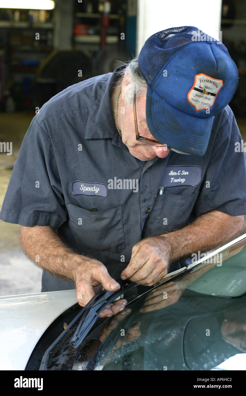 Elderly Gas station attendant fixing broken windshield wiper Stock