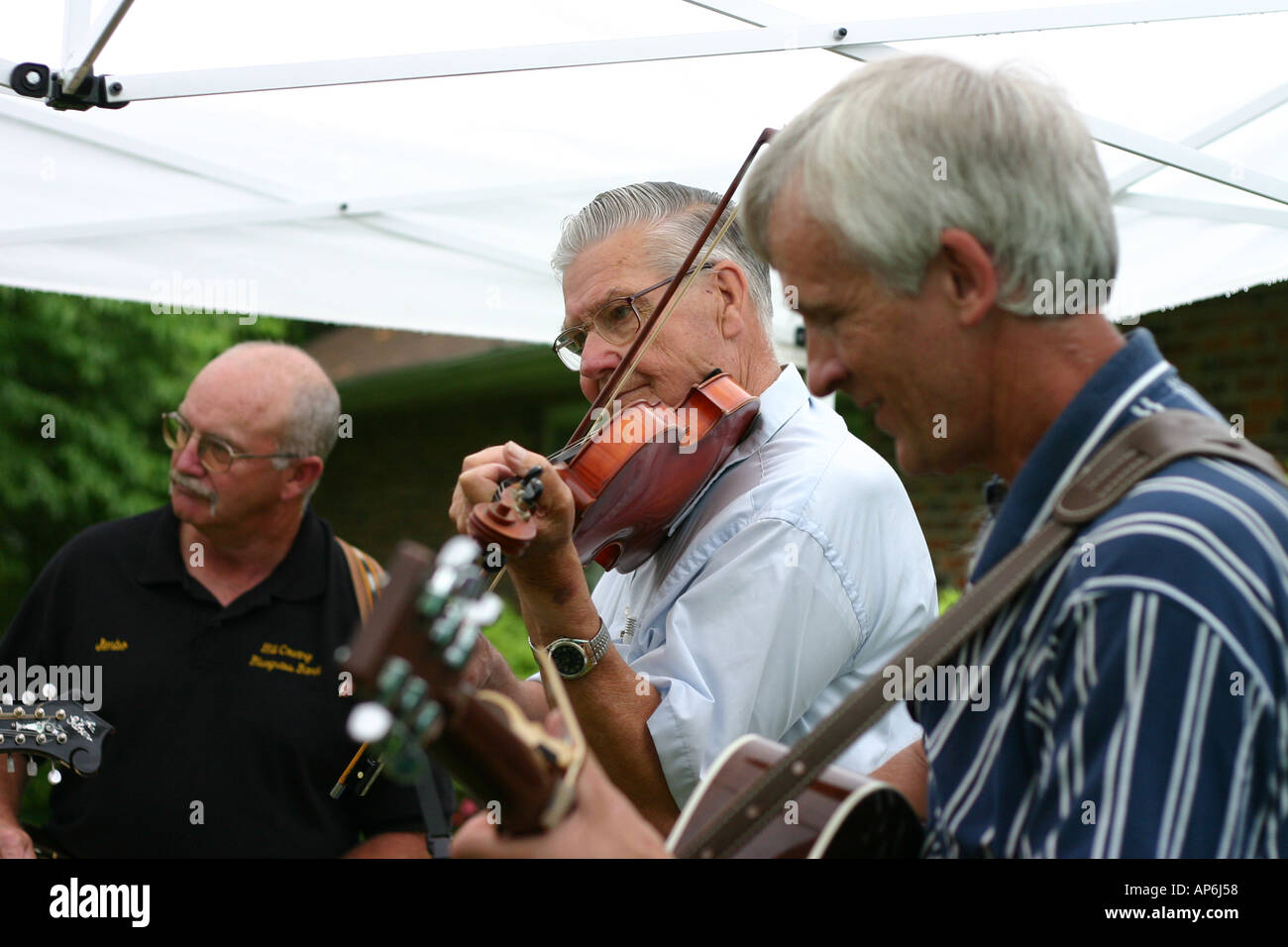 Older men playing the violin under a tent at a wedding Stock Photo
