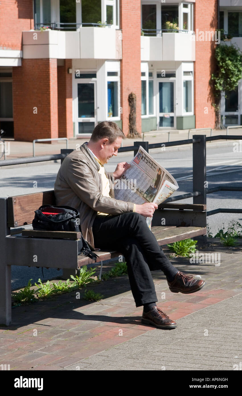 Man reading newspaper on a park bench Stock Photo - Alamy