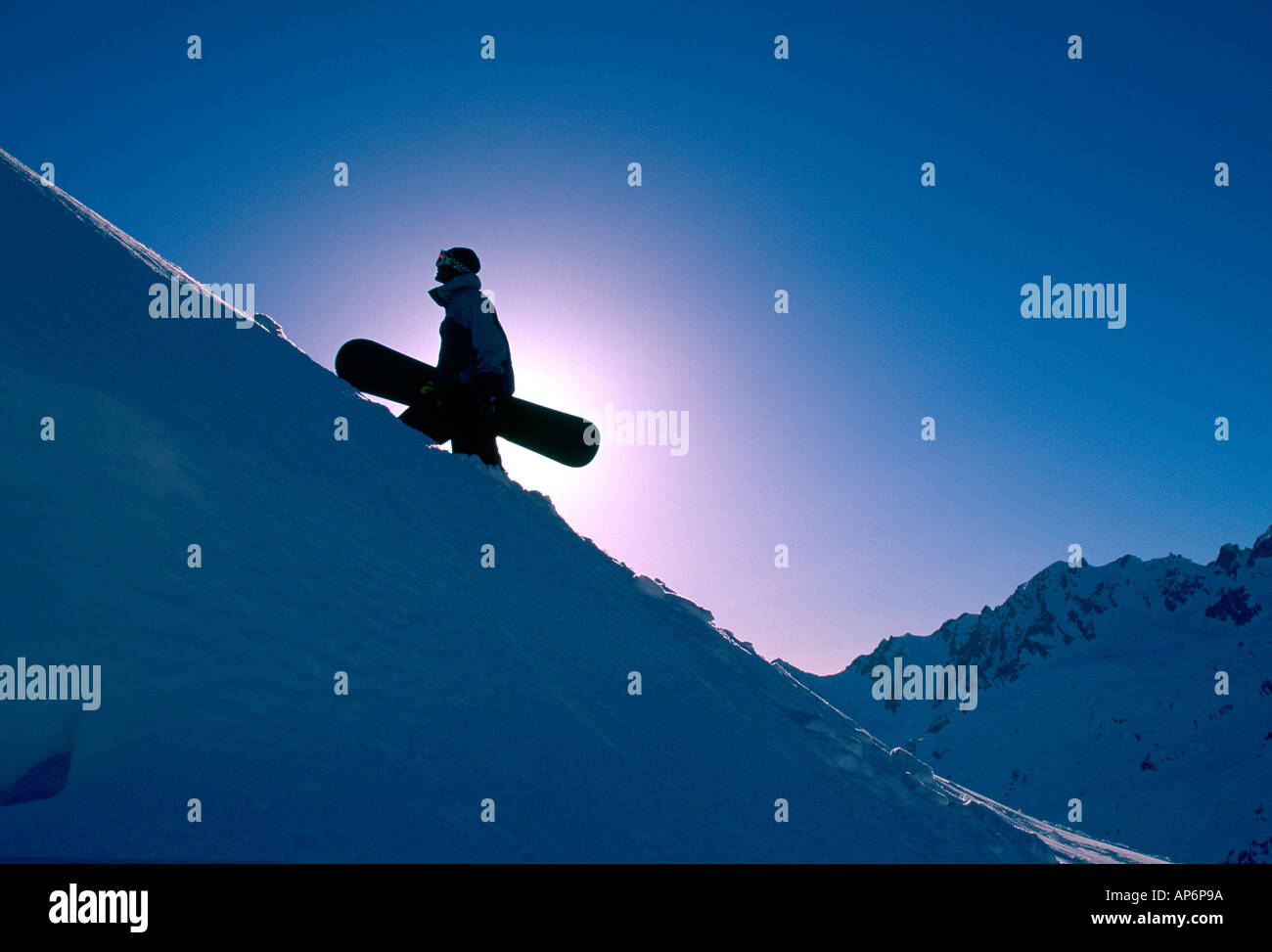 Backlit snowboarder hiking uphill, Chamonix, France Stock Photo