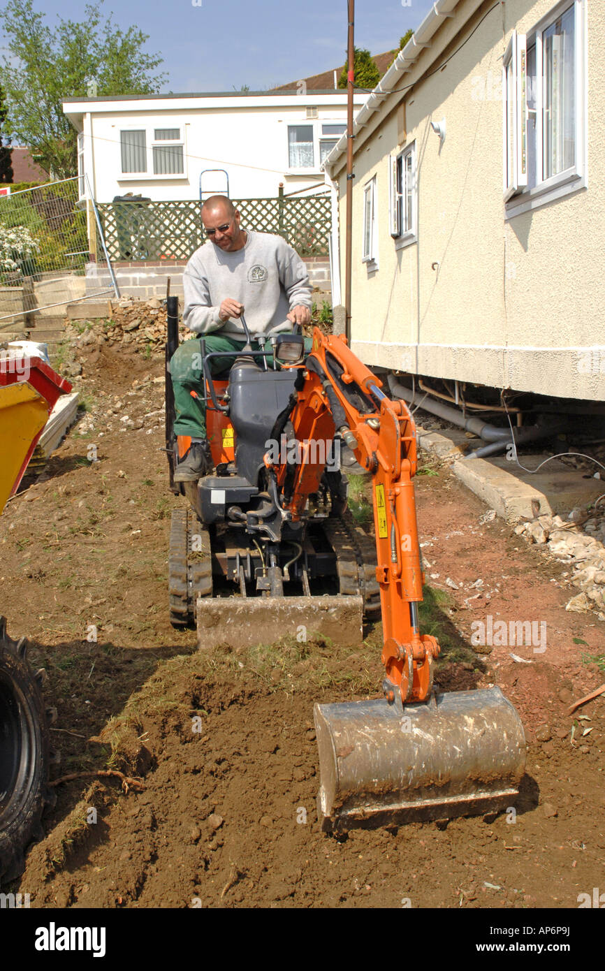 A mini digger excavating soil from a garden Stock Photo Alamy