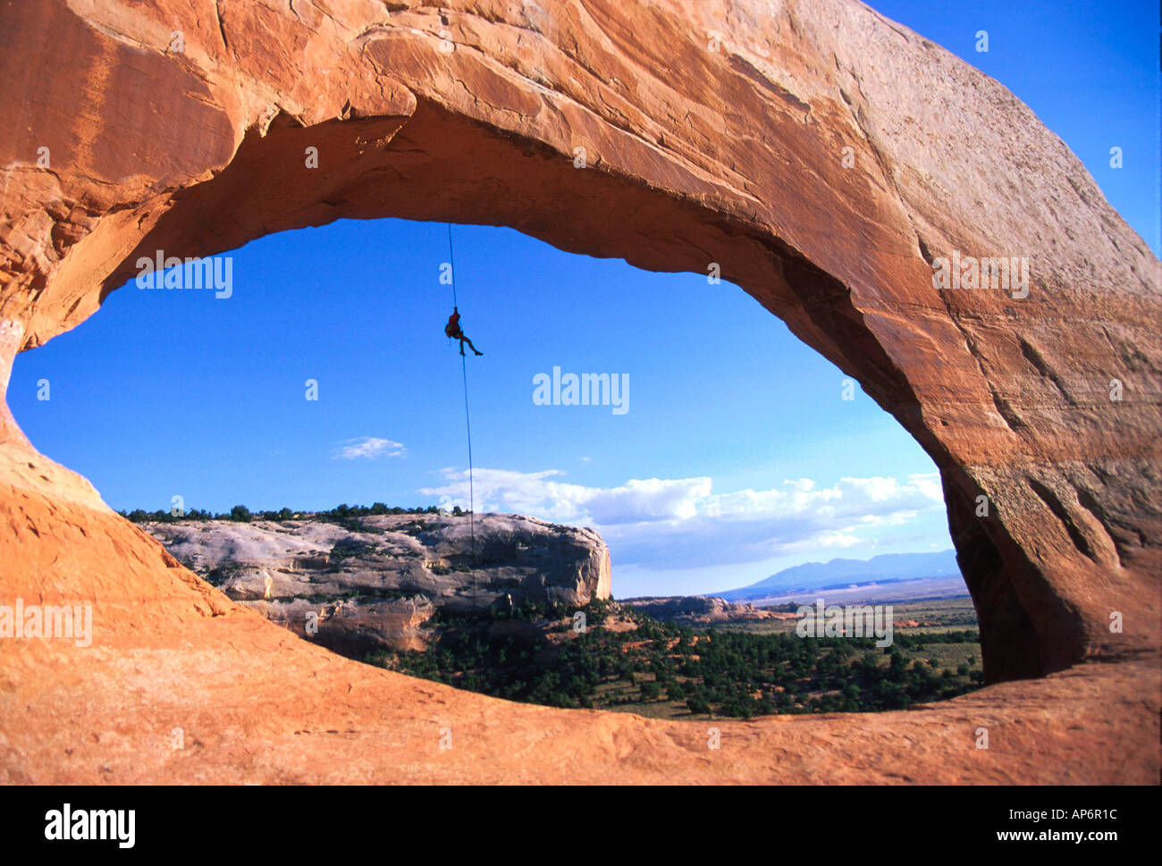 Man abseiling through natural arch in Fisher Towers, Colorado River Waterway near Castle Valley, Moab, Utah, USA Stock Photo