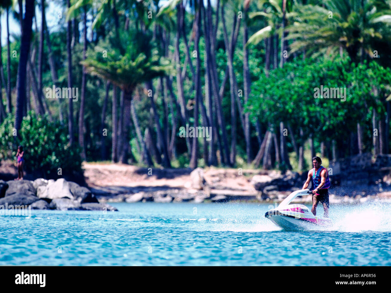 Jet ski in front of palm tree lined beach blue sea waves sand tropical