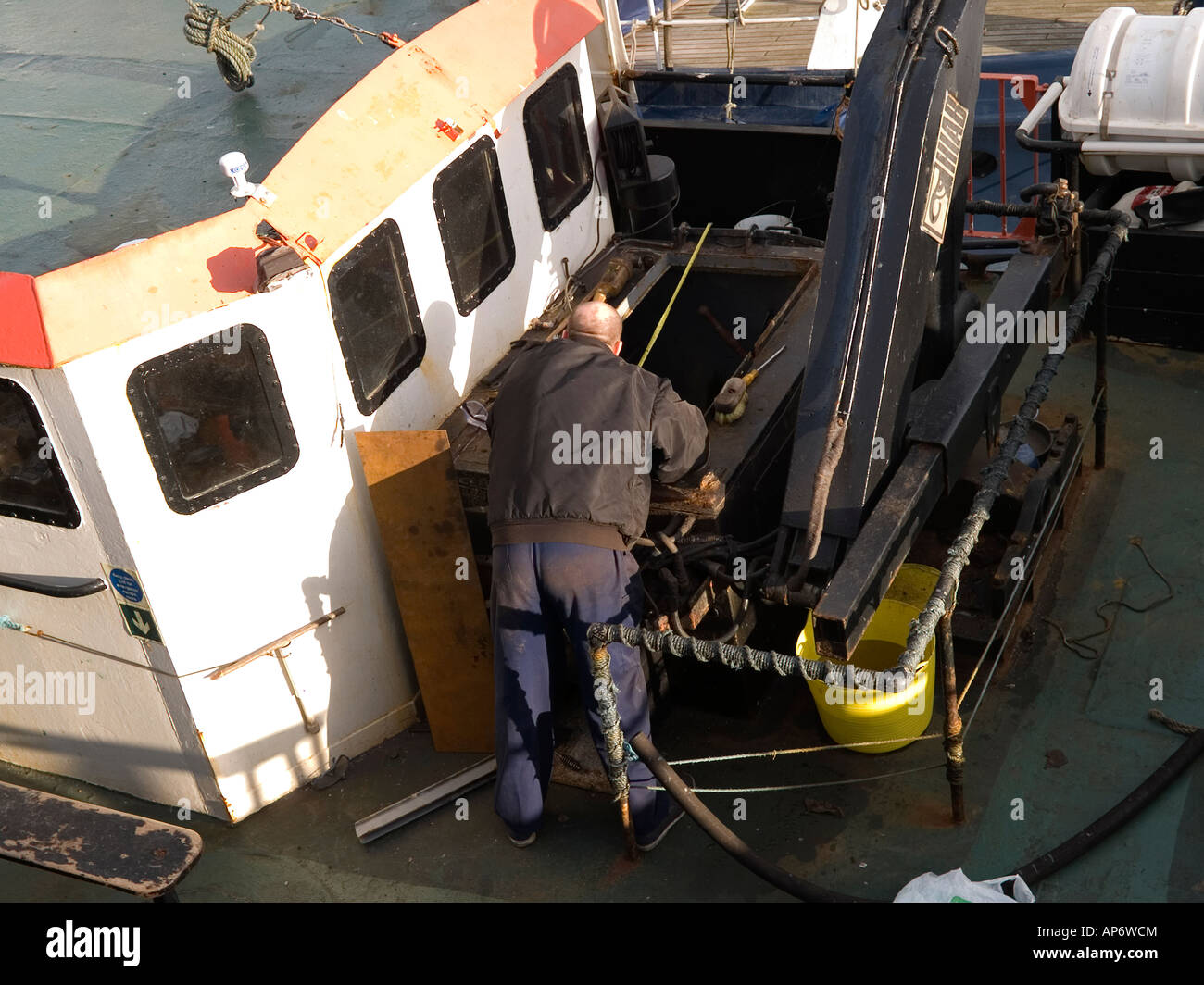 A workman looking down into the engine room hatch of a fishing boat