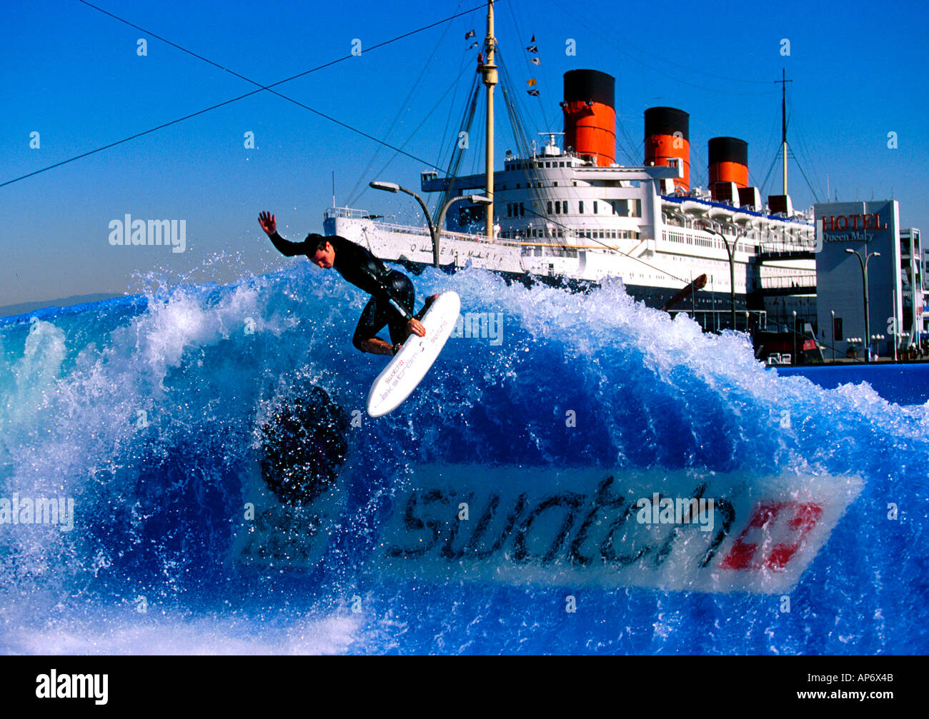 Surfing on artificial waves Longbeach, California, USA. With Cunard RMS Queen Mary in background and Swatch logo Stock Photo