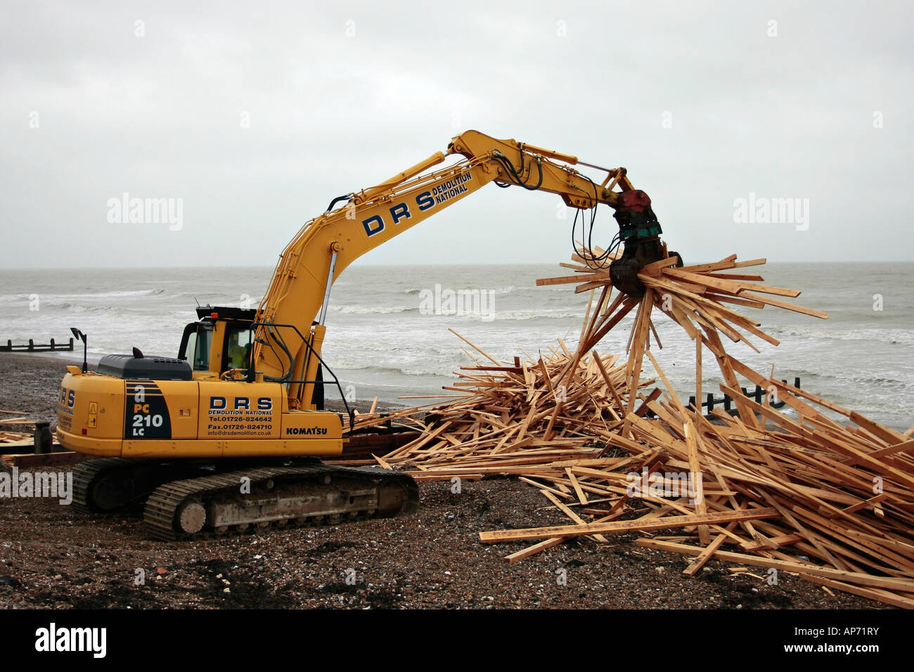 Komatsu PC210 LC crawler excavator clearing up wood from the wreckage of the cargo ship 'Ice Prince'. Worthing beach West Sussex Stock Photo