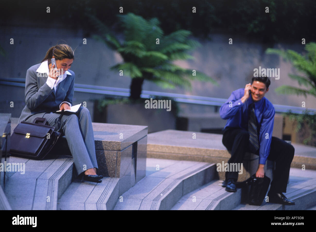 Business people with cellphones and briefcases on steps in downtown Los Angeles Stock Photo