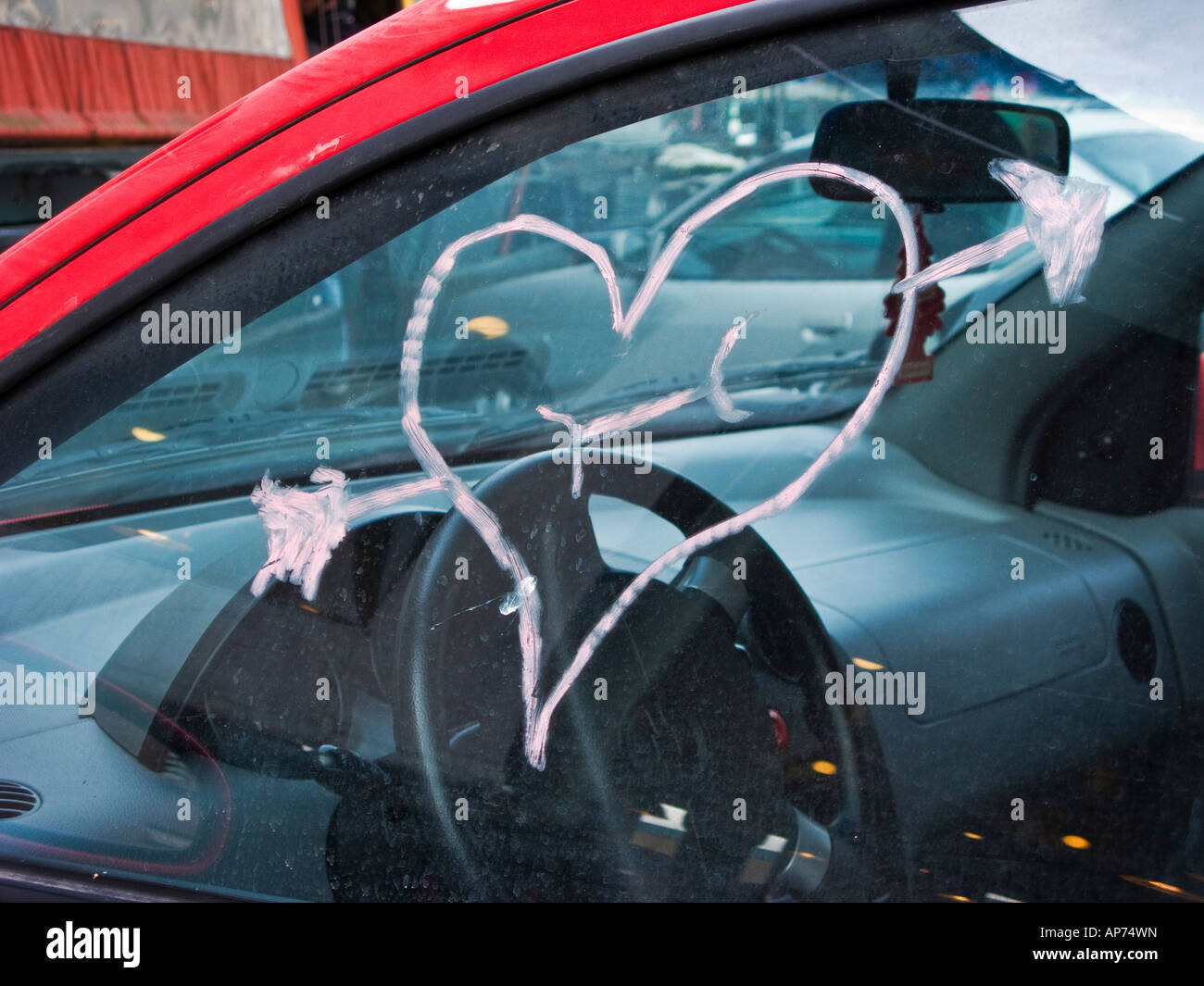 Red heart and Cupid arrow drawn with lipstick on car window Stock Photo